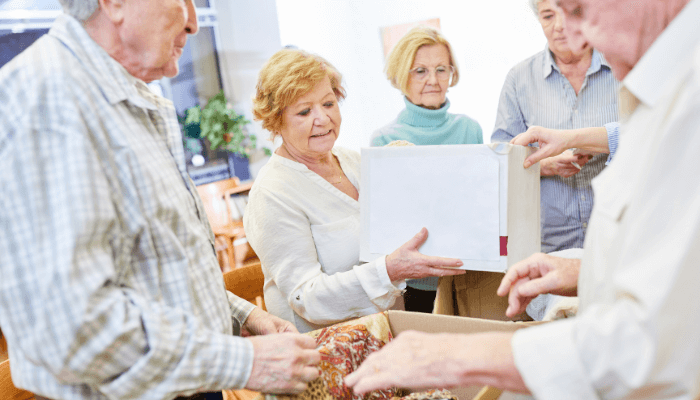 A group of male & female seniors opening a box & viewing its contents