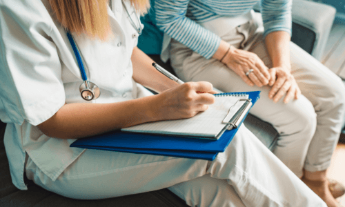 Health care professional taking notes while sitting with patient