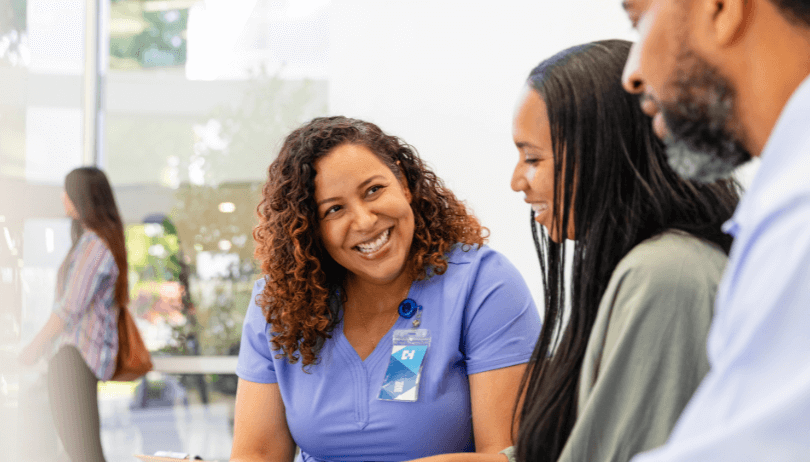 Adult female medical professional explaining medical chart to adult couple